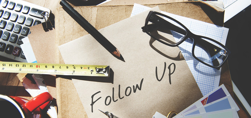 follow up note on desk with pencil, ruler, and reading glasses