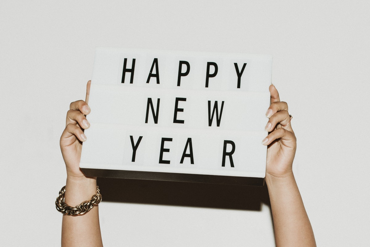 woman holding up a happy new wear letter board sign