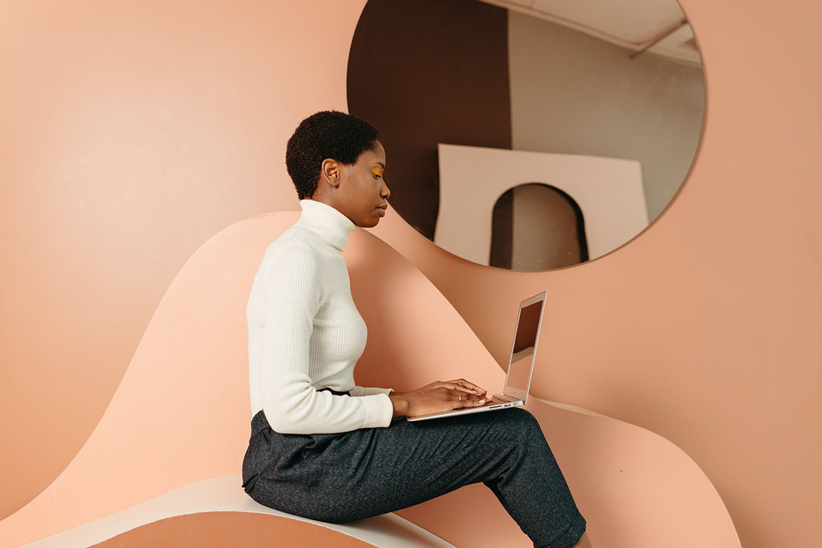 woman typing on laptop while sitting on modern furniture
